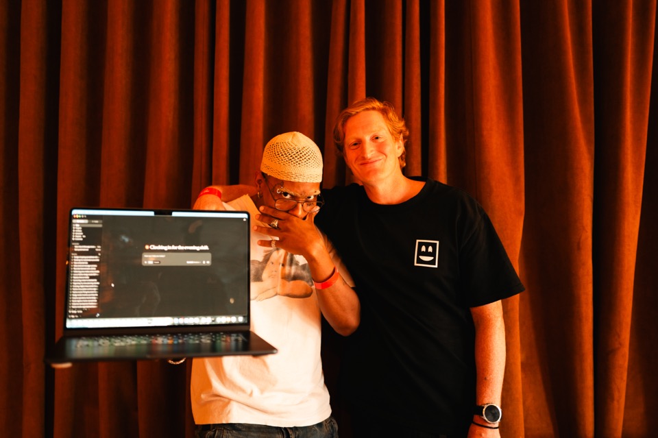 Two Light School members showing the app they built on a laptop